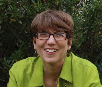 woman in green jacket smiling with glasses